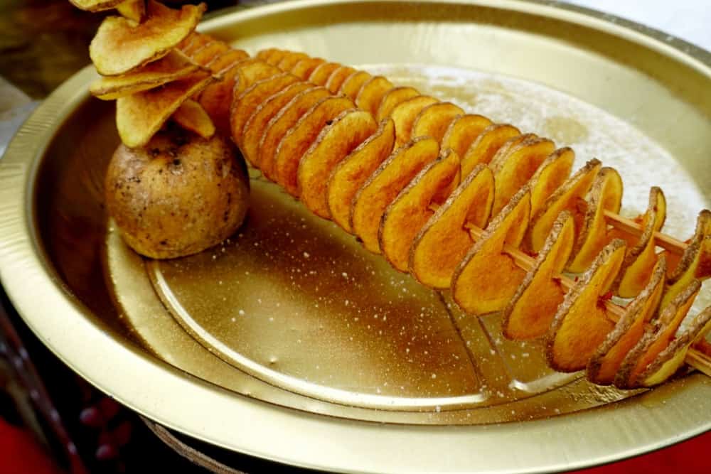 Deep fried skewered potato tornado served on a brass plate.