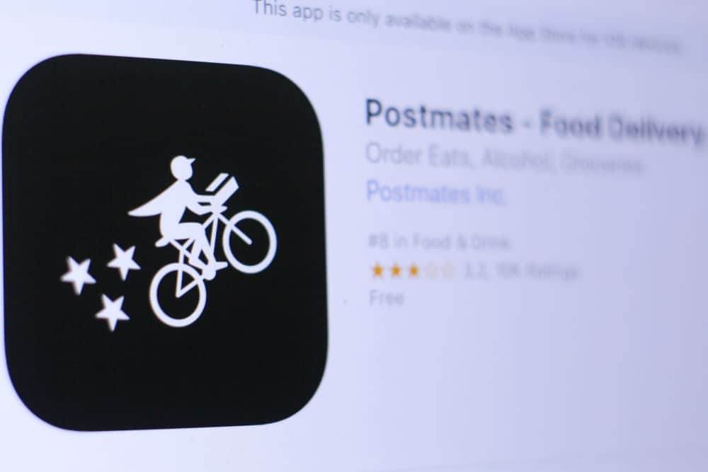Postmates logo and homepage on a digital screen.