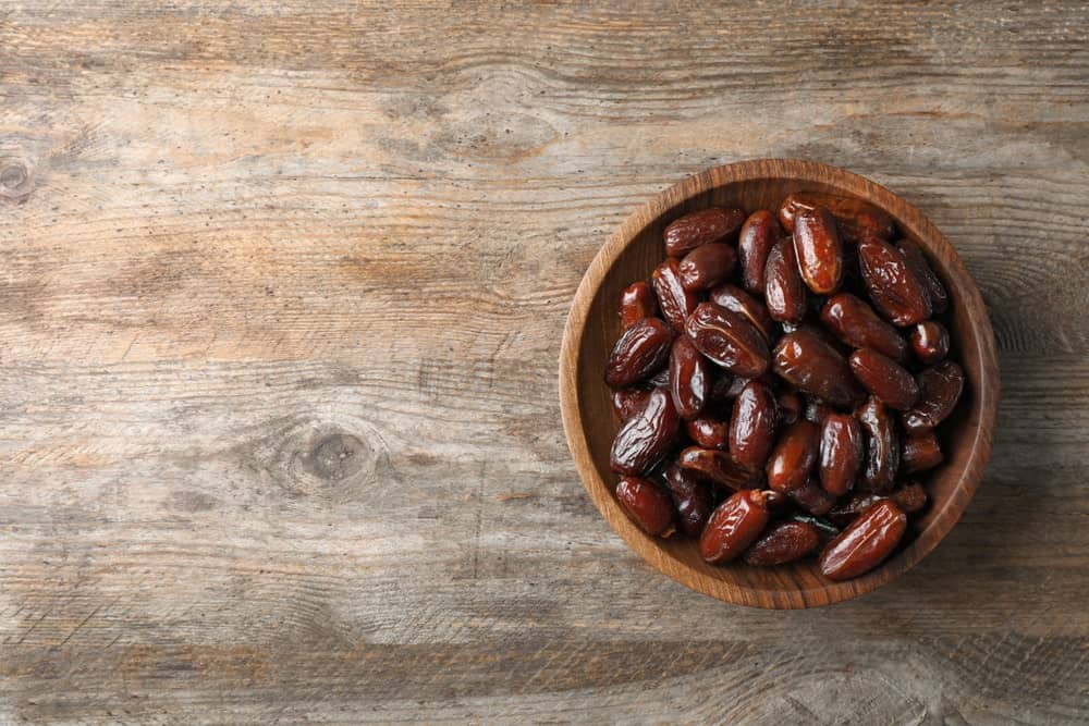 A wooden bowl filled with sweet Deglet Noor Dates.