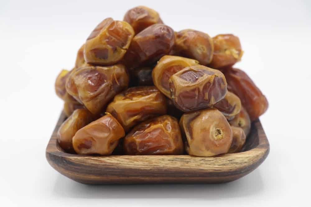 A close-up look of a wooden plate filled with Sukkari Dates ready to eat.