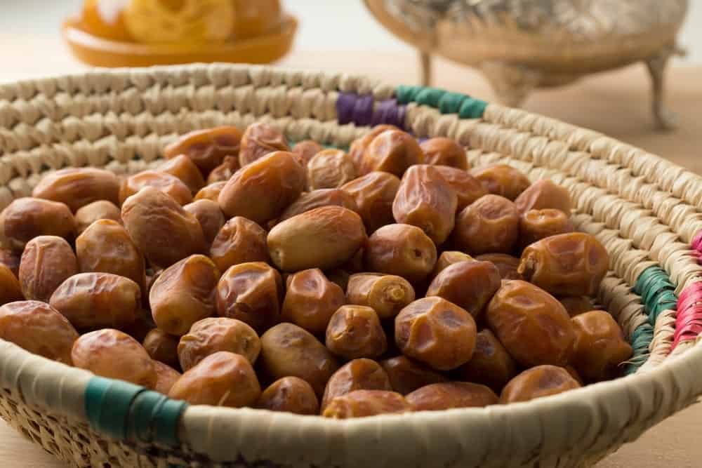 A heap of dried Zahidi Dates on a woven wicker basket.