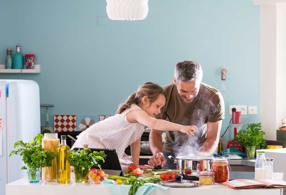 A father and daughter cooking in the kitchen.