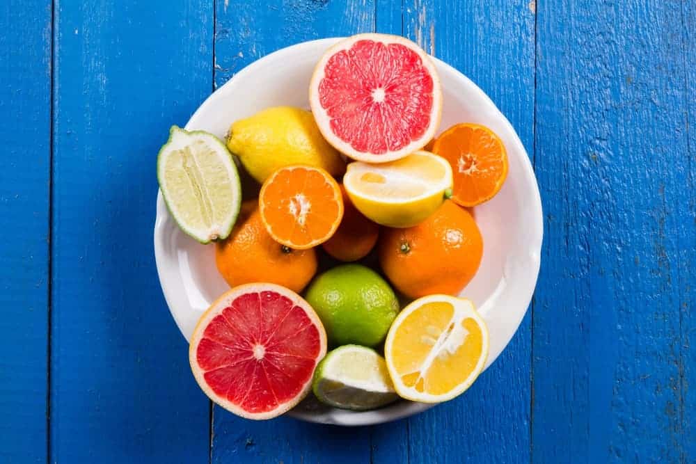  A plate of citrus fruits on a blue wooden desk.