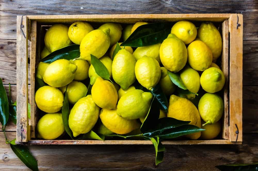 A crate full of lemons on a wooden background.