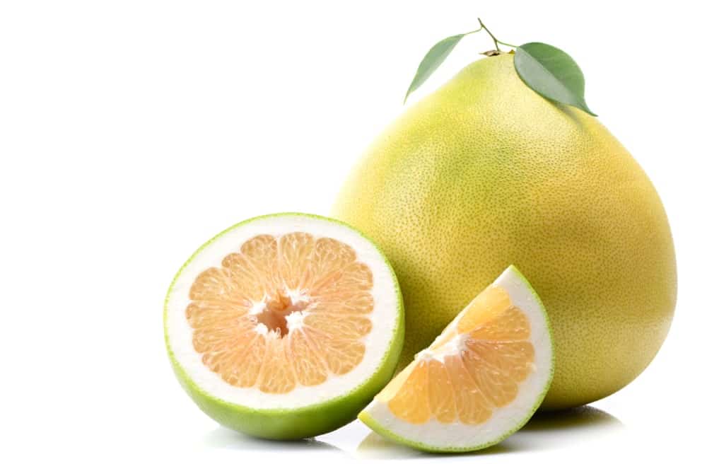 A whole Pomelo fruit and slices of pomelo.