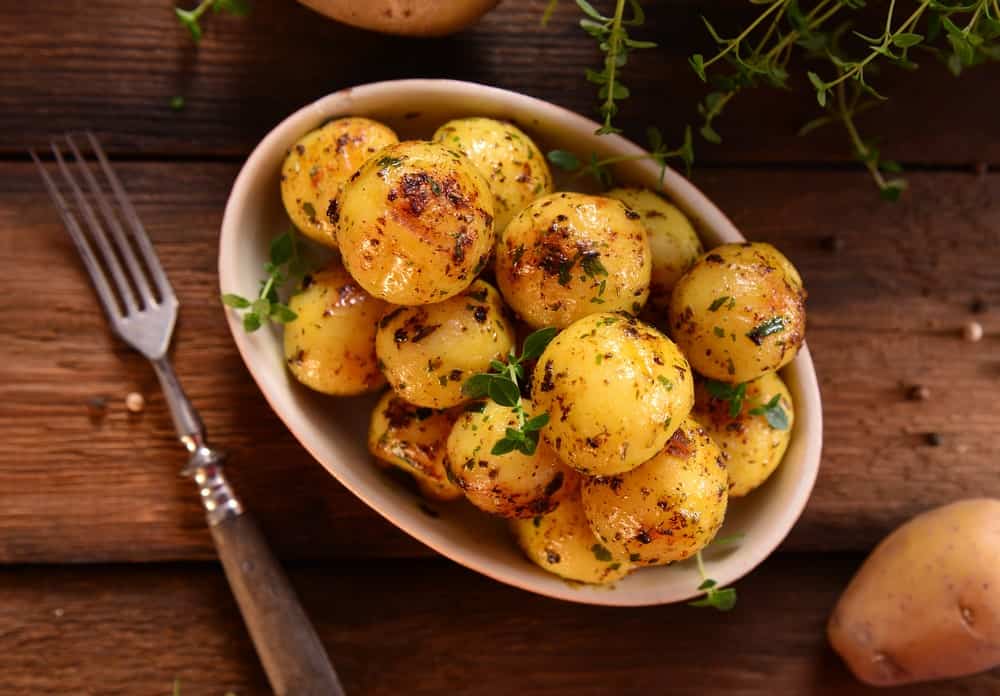 A bowl of baked potato marbles on a wooden background.