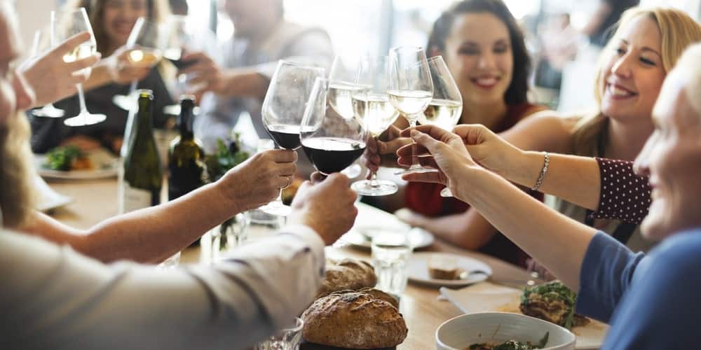 People at a dining table toasting with their wine glasses.