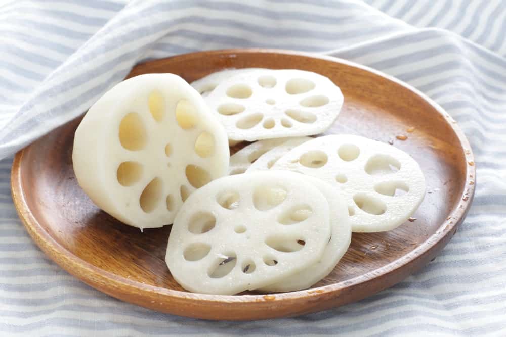 Sliced lotus root vegetable on a wooden plate.