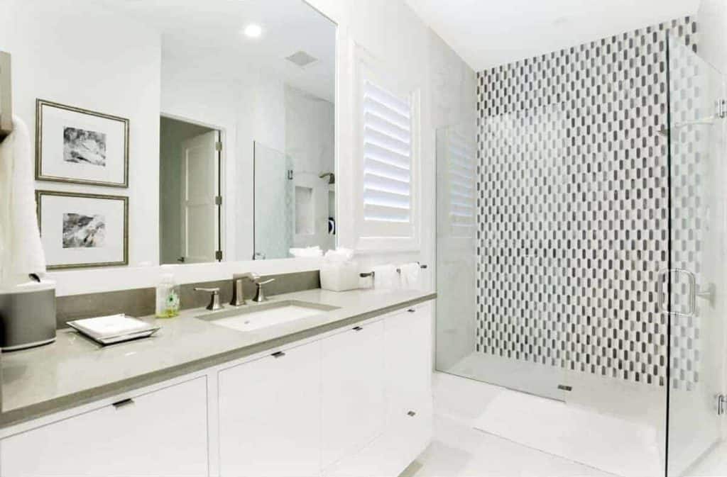 This stylish bathroom has marble countertop vanity and inset sink. This primary bath revolves around the clear glass paneling that encloses the huge walk-in shower.