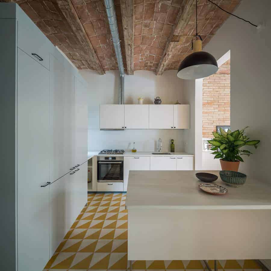 You can also go with mid-century modern kitchen design for a more homey feel. This kitchen has a simple white pantry and counter with a sink and oven. Its yellow and white tiled flooring gives the kitchen a nice touch of color.
