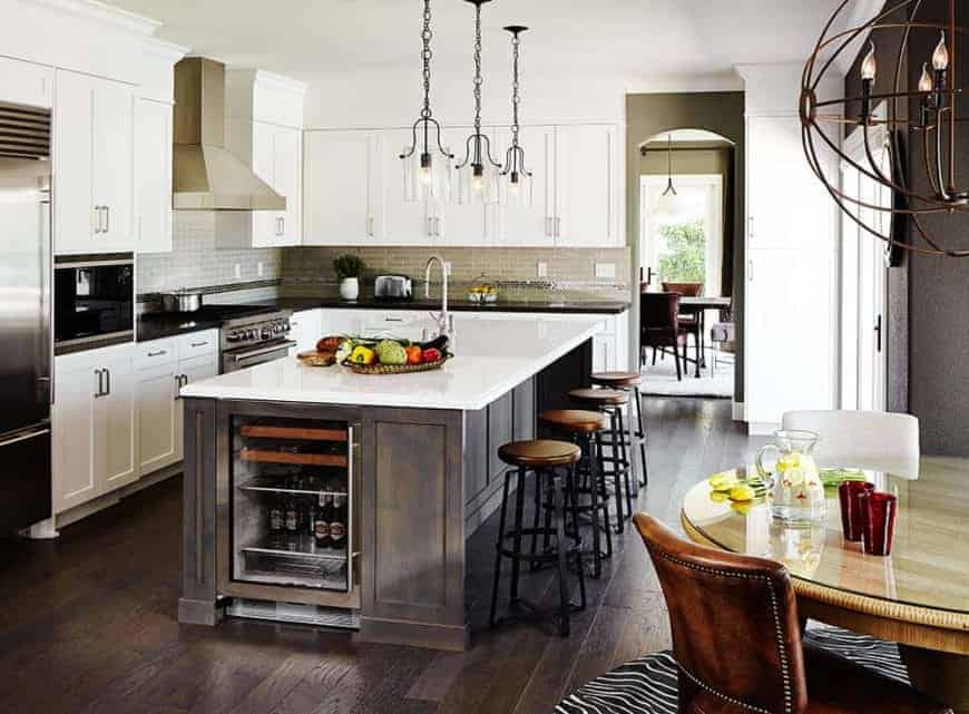 Fancy a country style kitchen? This kitchen can show you how! It has a dark wood island frame with a white countertop, which goes well with the hardwood flooring and the fancy brass pendant lights. Consider this an open kitchen with its smooth transition to the dining area.