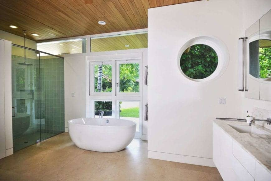 A wooden ceiling bathroom and white walls with a window with a great view outside. This room also features a single basin sink countertop match the marble flooring.