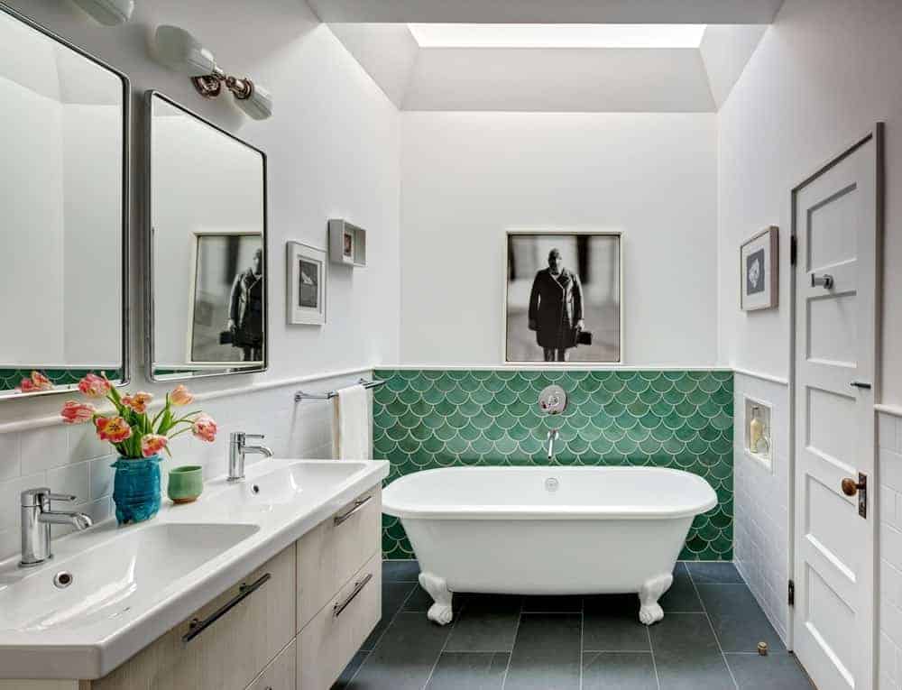 Small modern bathroom highlighting double basin sink countertop match the stylish marble flooring. This bathroom also has a stunning bathtub and a white walls with wall decors.