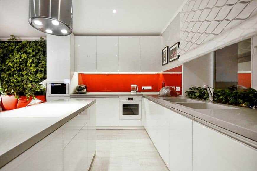 Sleek, urban, and eclectic - these must be the perfect words to describe this contemporary kitchen. It has white counters with a grey top, and a bright red splashback for that pop of color, making it both fashionable and refined.