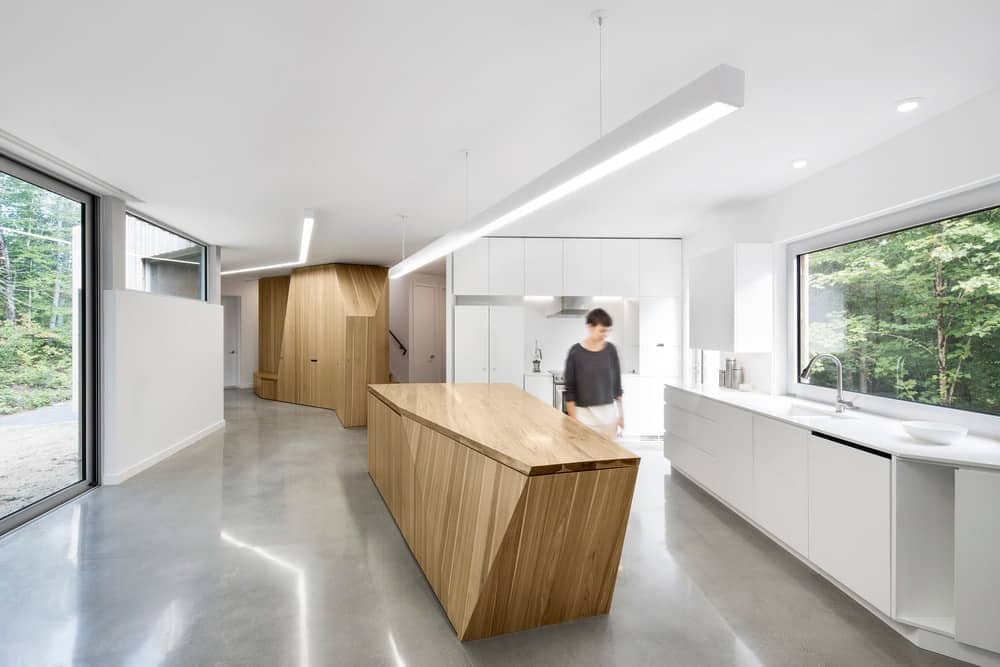 Going for a minimalist kitchen design? Go for something with neutral colors like this all-white kitchen with its grey flooring and wooden island and cabinet. The glass window and door also leave a simplistic design for a more refreshing take.