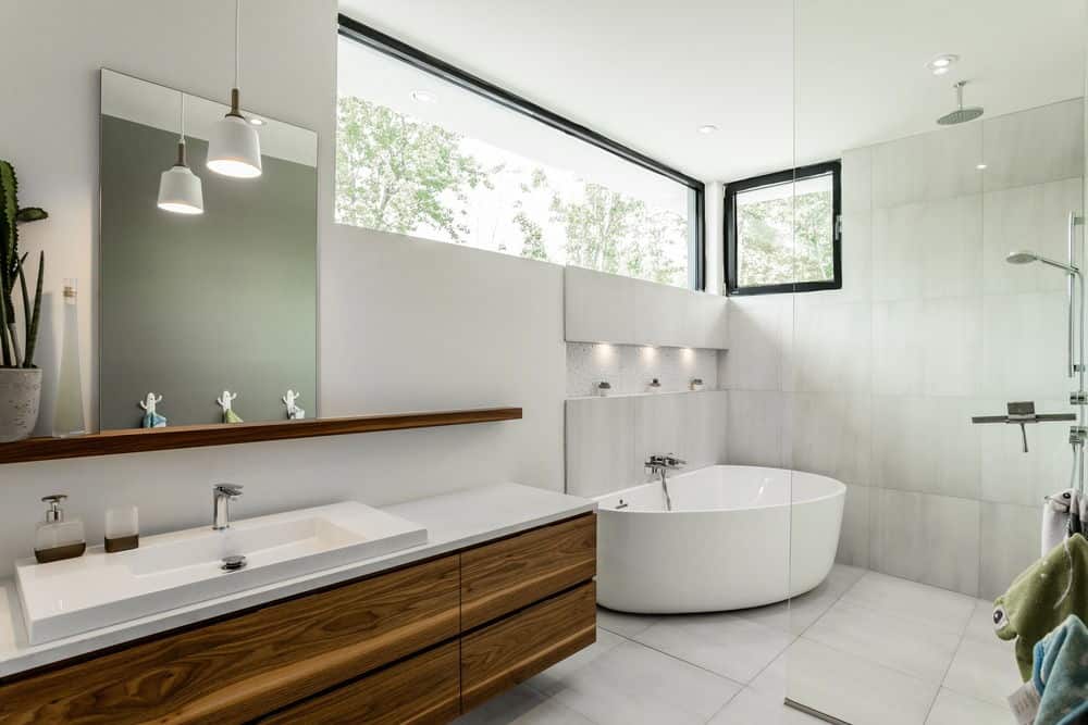 tylish bathroom with glass panel enclosed shower with bathtub. A rustic wooden vanity with a modern square basin sink brightens by hanging lights.