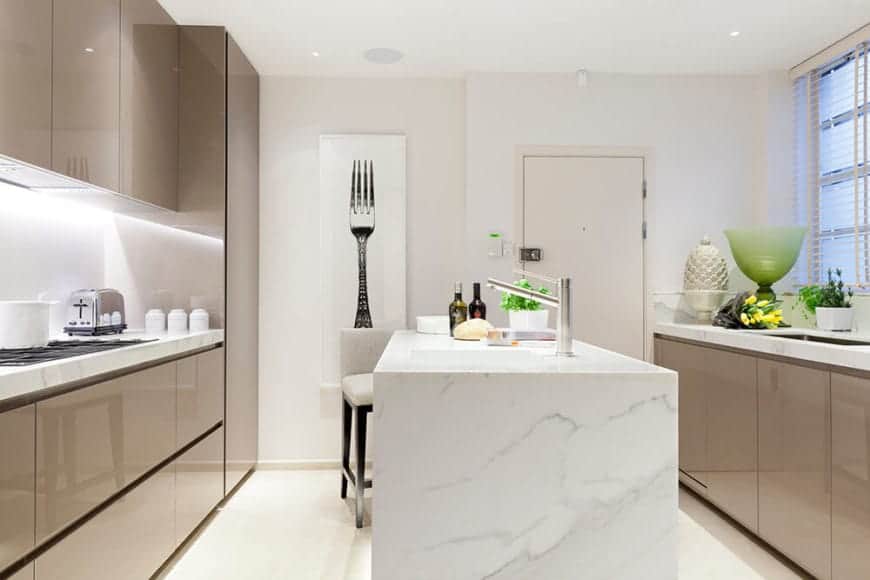This minimalist kitchen has a marble designed peninsula, which goes well with the tan drawers on the sides. The wall lights provide ample lighting by the sink. For a personal touch, the kitchen has a tasteful fork art on the wall.
