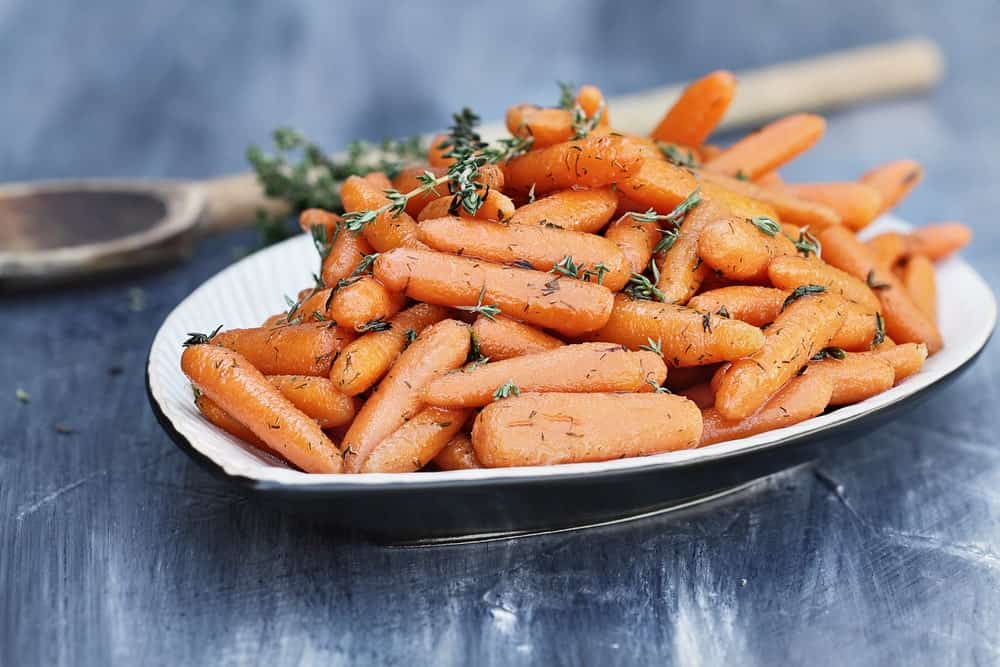 A plate of honey glazed herb baby Imperator carrots ready to eat.