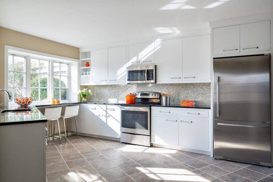 This kitchen has a modern Asian style with its tiled flooring, white counters, and steel fridge. Right by the window pane is the breakfast nook where one can enjoy the sunlight and the view while having a nice meal. The fresh flowers give a lovely finish to the whole kitchen.