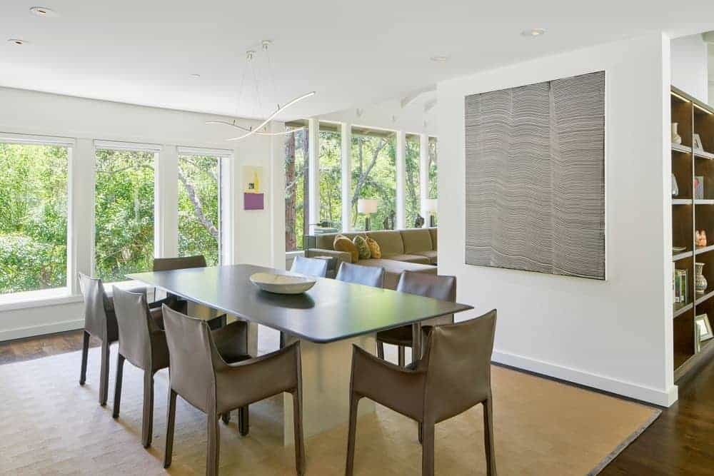 This view of living space with a couch and dining area with modern tables and chairs on the carpet. This room features hardwood flooring and a window with a great view outside.