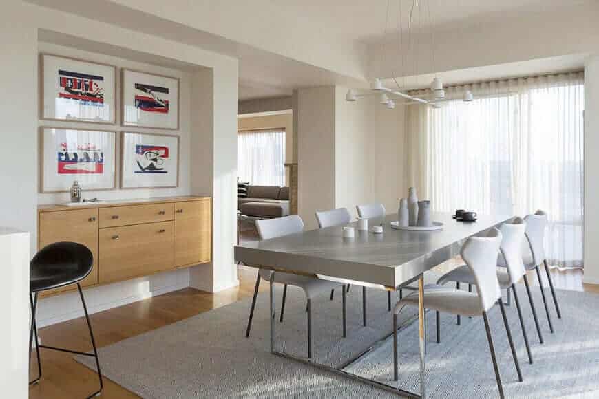 Dining area highlighting stylish tables and chairs on the rug. This room also showing hardwood flooring and a white wall with gorgeous interior design.