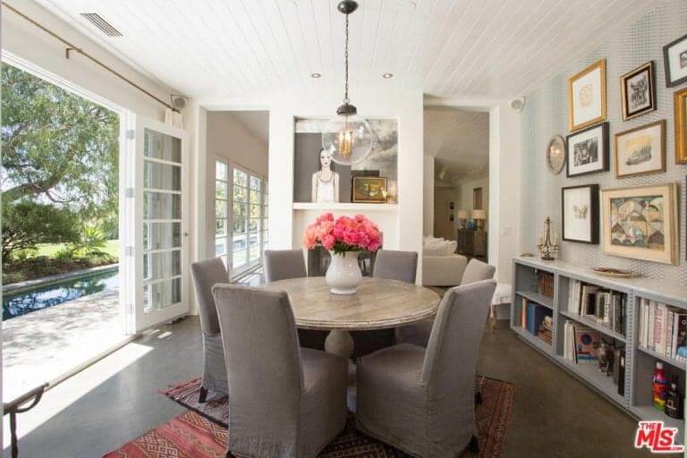 Small round dining table with grey chairs on the rug in front of the door with a great view outside.