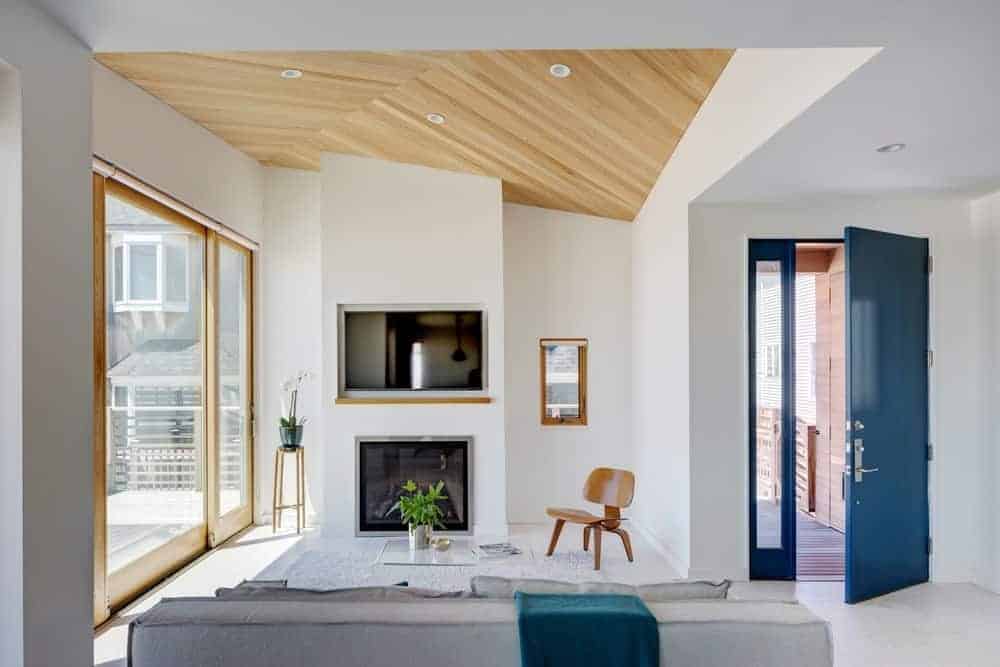 Small yet appealing living room highlighting comfy sofa set and a modern fireplace under the TV. This room also has a glass wall with a great view outside.