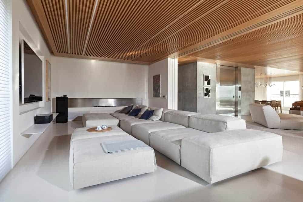 This front view of the living room featuring a white sofa set in front of the TV. This room white walls and wooden ceiling.
