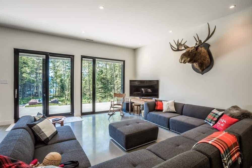 Contemporary living room highlighting a classy U-shape grey sofa set ringed by the white ceiling and white walls with reindeer head design.