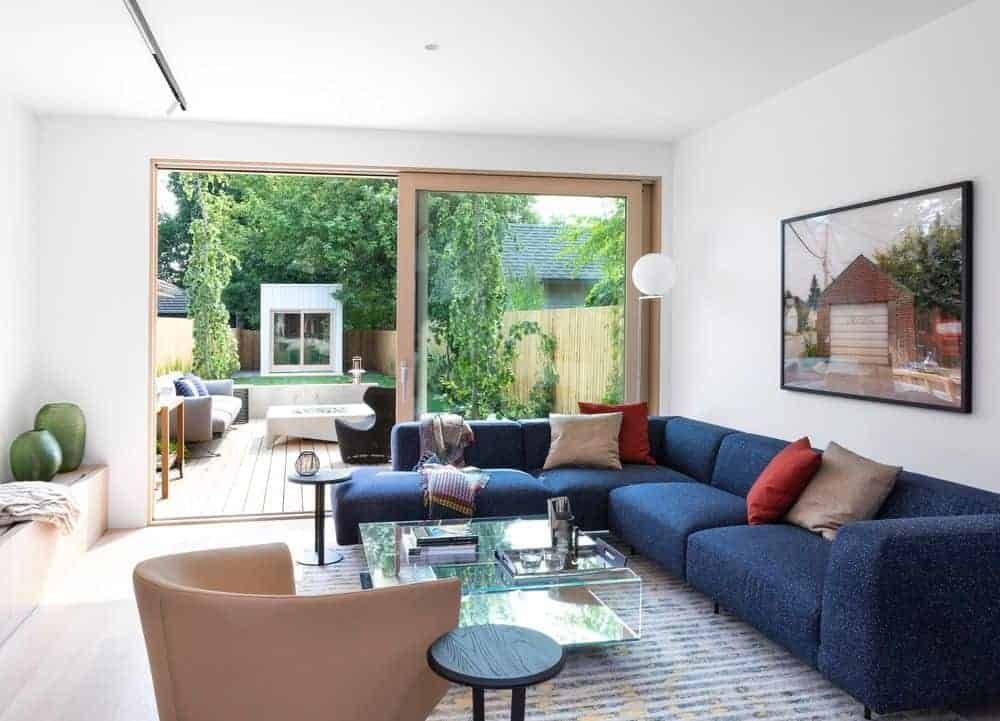 Small living room with blue L-shaped sofa set and glass table on the rug. This room has a sliding glass door leading to the terrace.