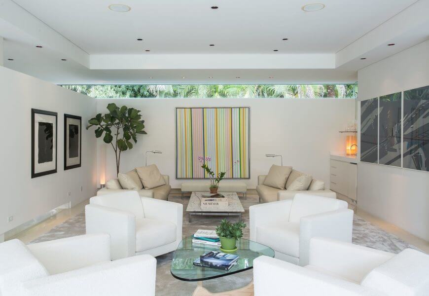 A formal living room featuring a charming sofa sets and attractive tray ceiling. The white walls look gorgeous with wall decors.