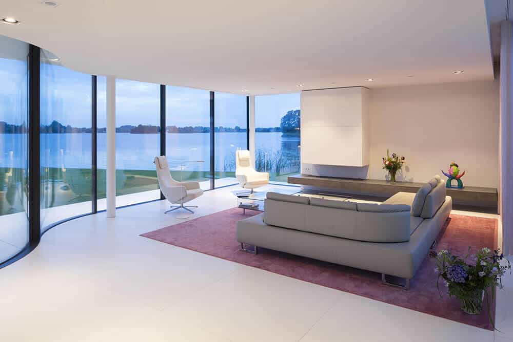This modern living room looks so attractive with its comfortable couch set and white wall and floors. This room has glass wall with an impressive view outside.