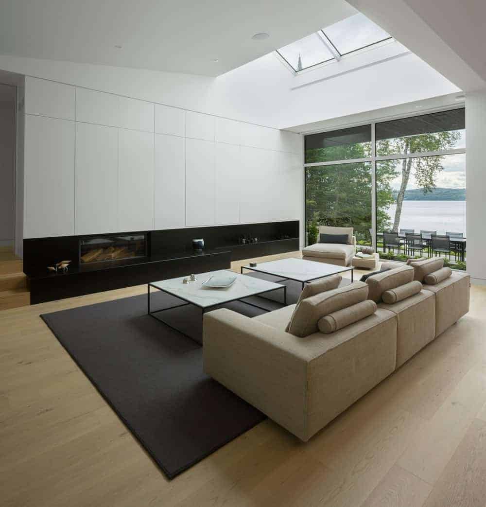 This living room looks perfect with its hardwood flooring and brown sofa set with a pair of a square table on the rug. This room has glass wall with a view of the backyard.
