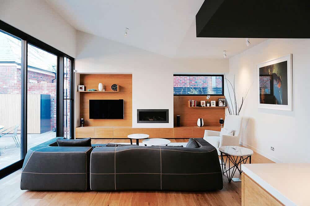A gorgeous living room with a classic black sofa set on the hardwood flooring surrounded with white walls and ceiling.