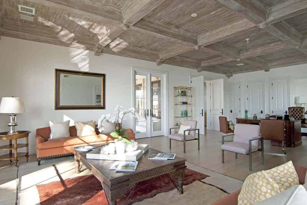 An open space concept features living space and office space. The living space has a cozy sofa set and a wooden table on the rug.