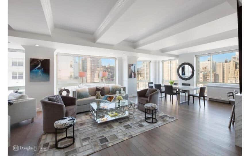 Modern home with an open space concept featuring living space and dining table set. This room features a glass wall with a building view outside.