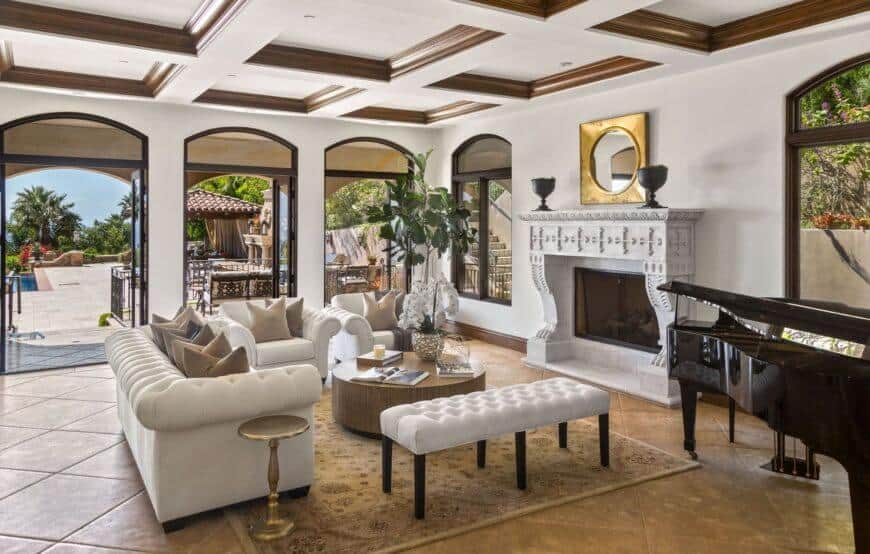The elegant mansion features a formal living space with a white sofa set and wooden table on the carpet. This room also features an elegant black piano.