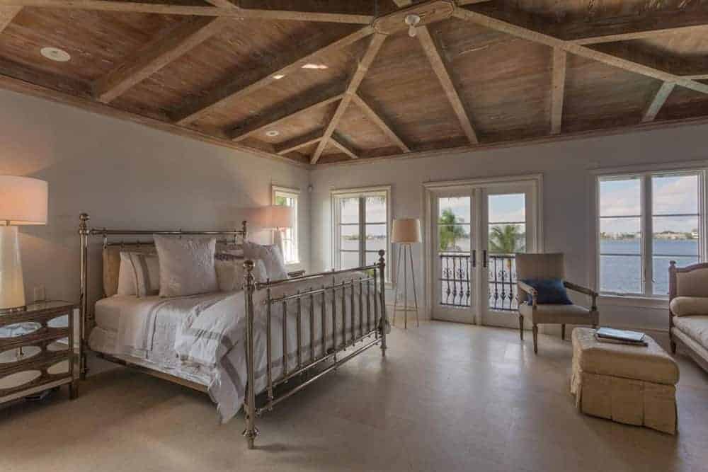 This master bedroom features an elegant bed and sitting area on the side. There are table lights and floor lights lighting up the room.