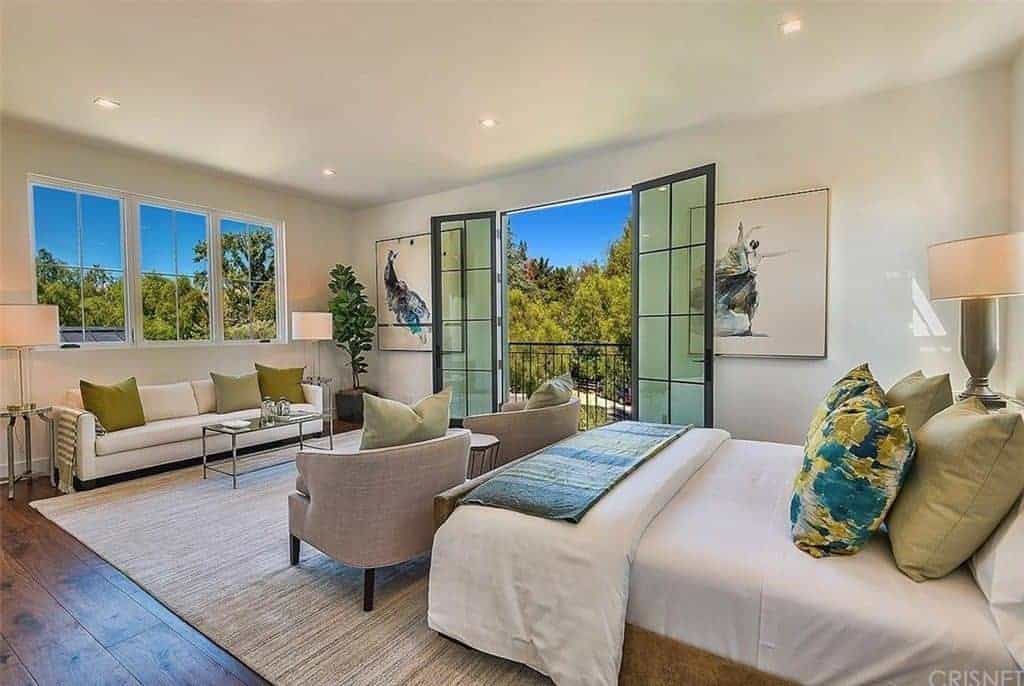 A master bedroom including modern chairs and white couch by the window with two-floor lamps on both sides. The room also has creative wall decors.