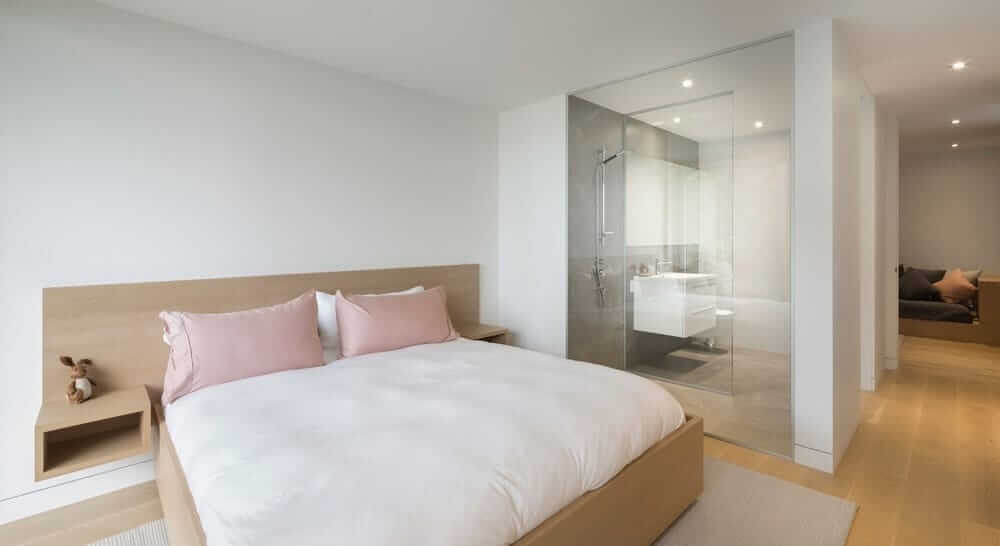 This master bedroom has its own living space and bathroom. It highlights white walls and hardwood flooring.
