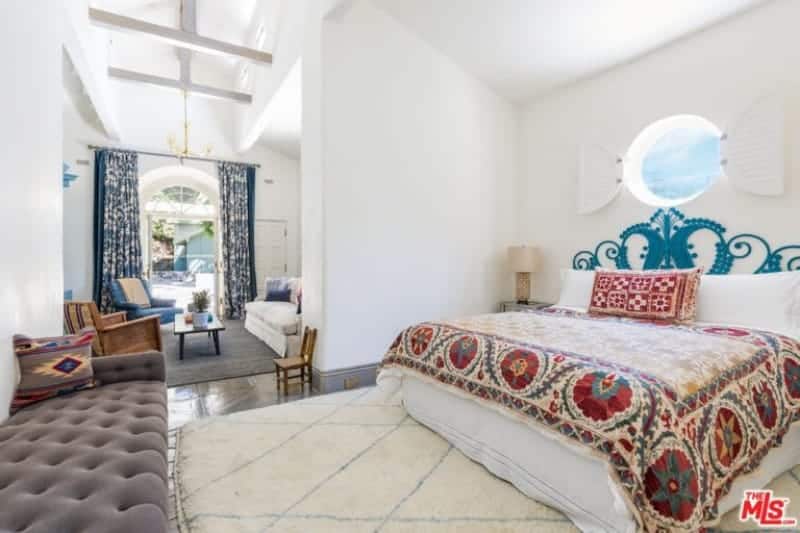 Large master bedroom with a stylish bed and a comfortable couch in front. The room also has its own living space.