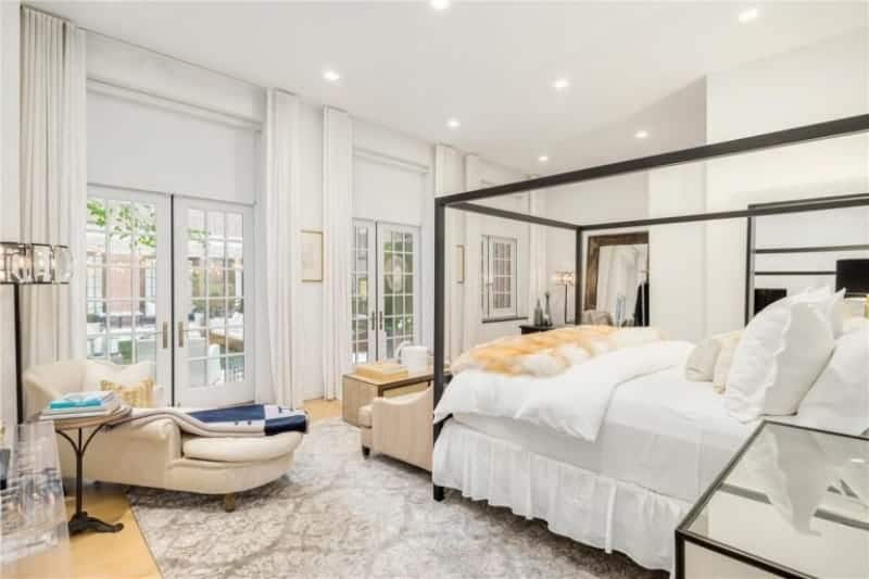 A gorgeous bedroom with stylish wall design and a fancy bed frame set on the hardwood flooring topped by a large area rug.