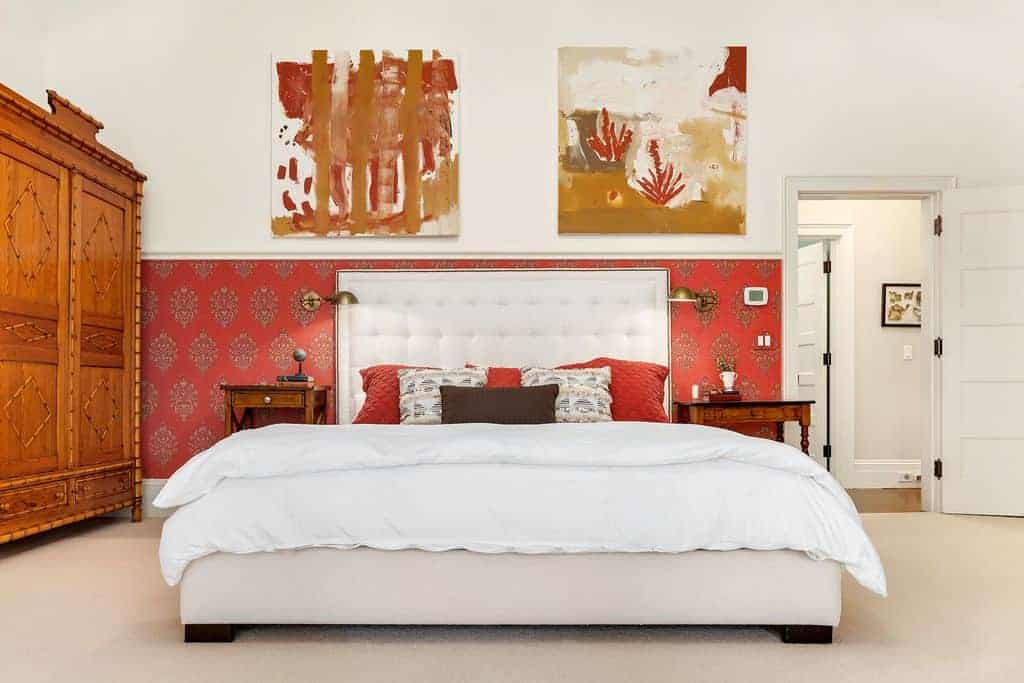 This white master bedroom offers a large bed with two built-in lamps besides. The room features white walls with wall elegant decors.