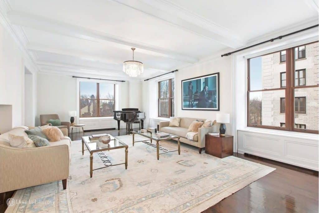 Modern living space with a comfortable couch and a couple of tables in the middle lighted by a stunning chandelier.