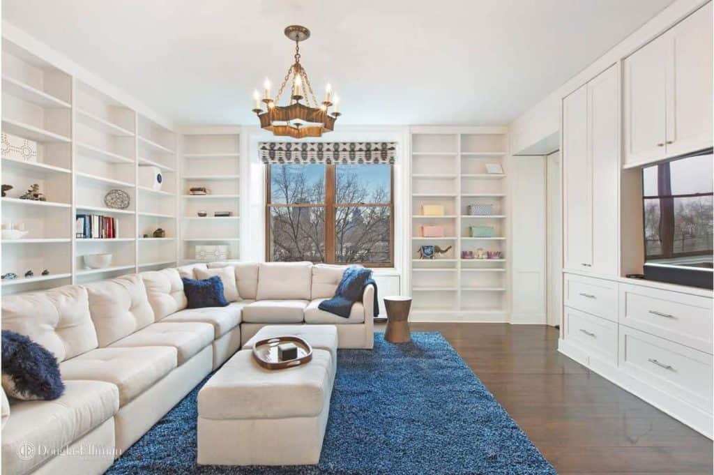 This formal living room is a place where book lovers will enjoy themselves with those multiple bookshelves and cozy sofa set on the blue rug.