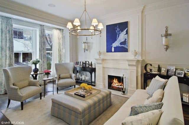 Contemporary living room with flush mount lighting and a stylish rug along with a fireplace and wide glass window. The wall decor adds style to space along with the chandelier.