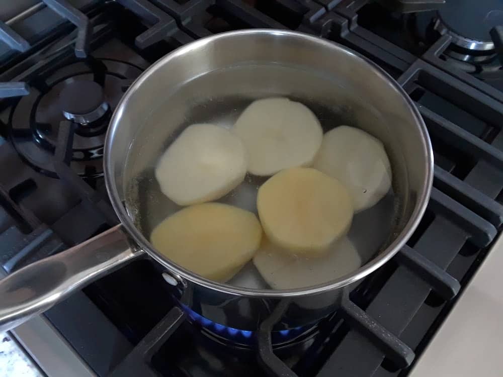 Potatoes that are boiling in a pan.