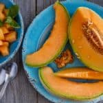 A plate of sliced cantaloupes on a wooden table.