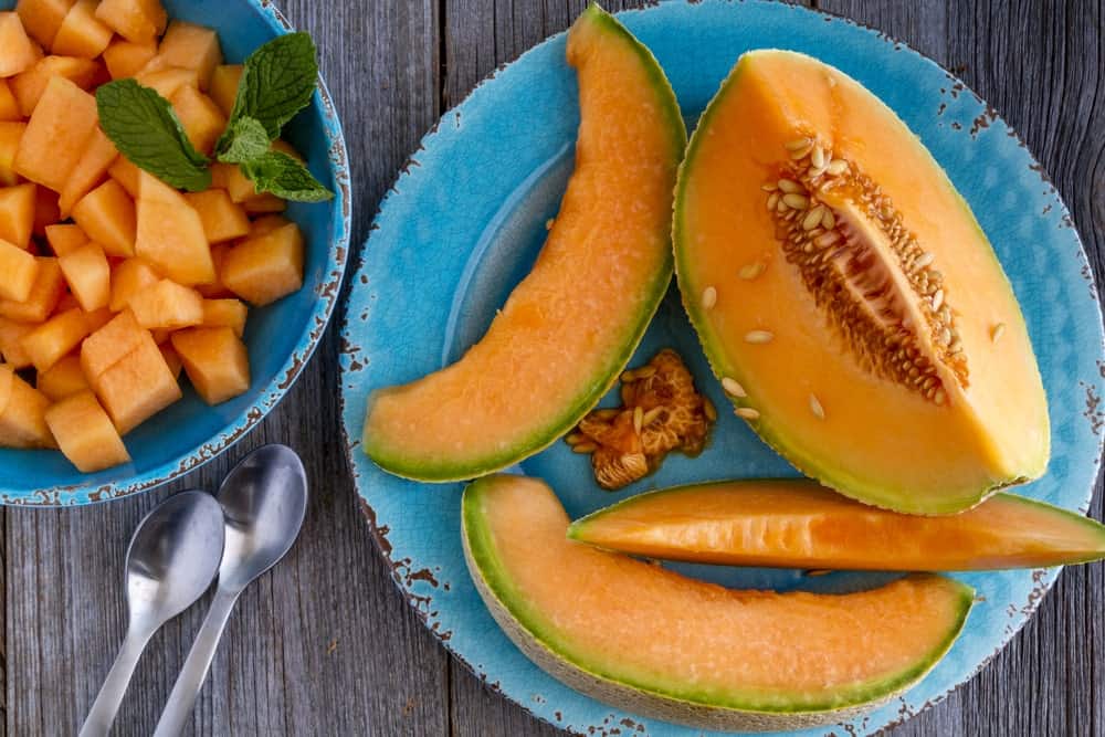 A plate of sliced cantaloupes on a wooden table.