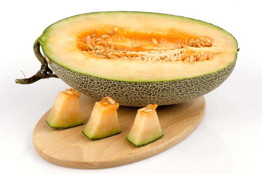 A plate of sliced cantaloupes on a wooden table.